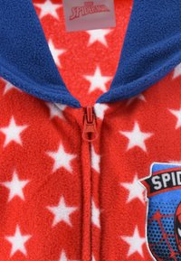 Red fleece onesie with white stars, a blue collar, and a front zipper. Features a Spider-Man logo patch on the left side.