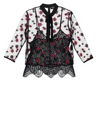Blusa nera in pizzo con motivo floreale rosso, con maniche lunghe, colletto e orlo scallop. Decorata con un fiocco al collo.