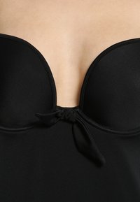 Top de fato de banho preto sem alças com copas moldadas, tecido suave, detalhe de laço central e design de decote profundo.
