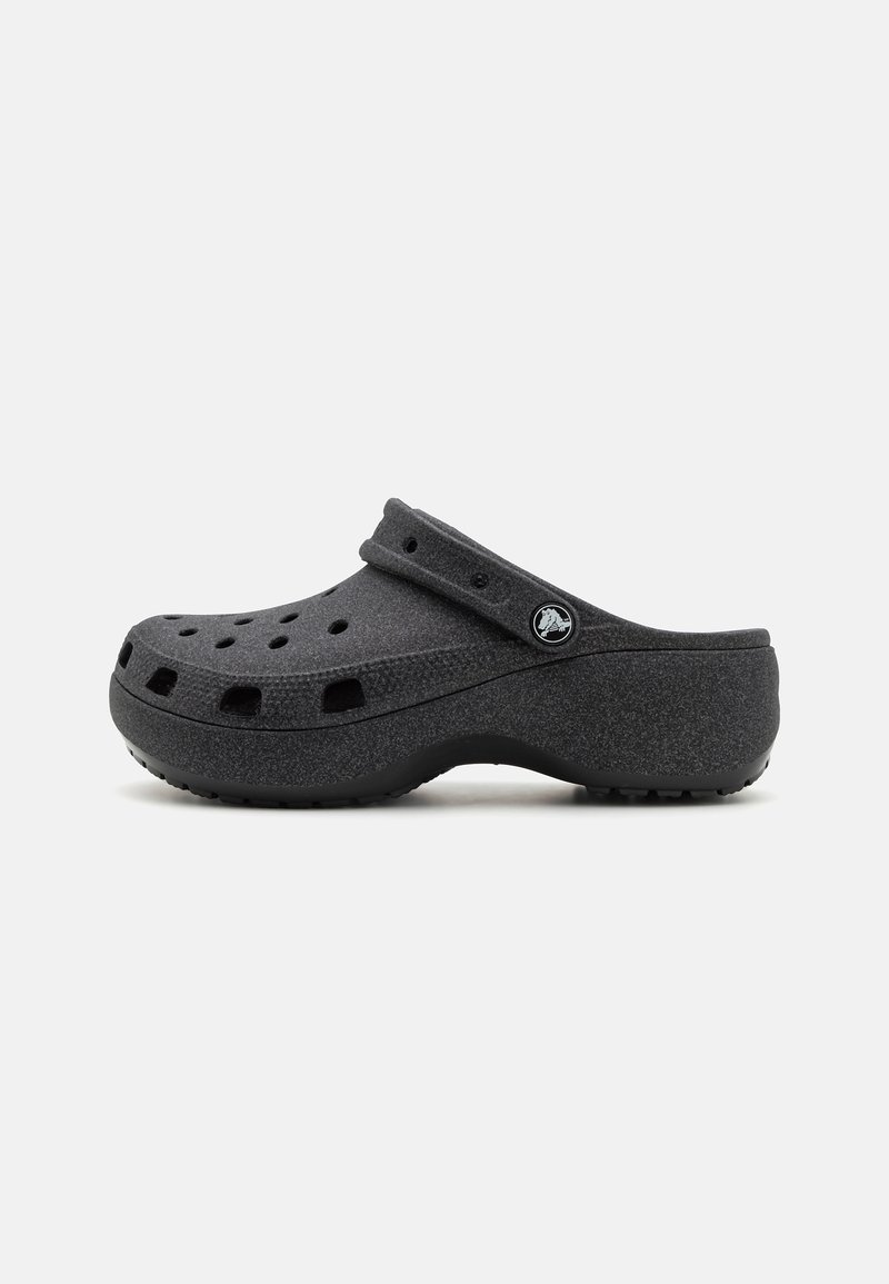 Sabot noir à enfiler avec trous de ventilation et bride de talon réglable, surface texturée et semelle en caoutchouc sur fond uni.