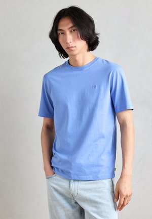 T-shirt a maniche corte di colore blu chiaro, realizzata in cotone, con scollo rotondo e un piccolo logo sul lato sinistro del petto. Vestibilità standard, texture liscia.