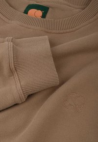 Beigefarbener Sweatshirt aus weichem Material mit gerippten Bündchen und Ausschnitt. Kleines Elefant-Logo ist auf der Vorderseite gestickt.