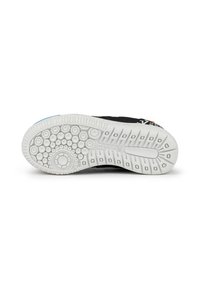 Suela de zapatilla negra con goma blanca texturizada, con patrones circulares y un acento azul. Logo visible en el lateral. Diseño duradero.