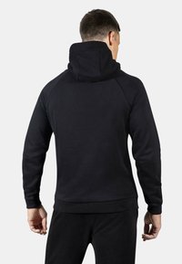 Felpa nera con collo alto e orlo a coste. Presenta maniche a raglan e una texture liscia. Design minimalista, senza loghi o motivi visibili.