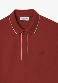 Marin polo skjorta med strukturerad stickad tyg, vit kontrasterande krage och knappslå, samt en subtil broderad logotyp på bröstet.