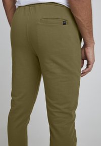 Olivgrüne Jogginghosen aus weichem Material, mit einer Gesäßtasche und einem kleinen Logotag. Figurbetonter Schnitt mit elastischem Bund.