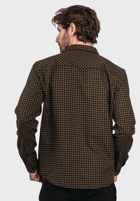 Herren Langarmhemd in Dunkelbraun mit gelbem Karomuster. Verfügt über einen klassischen Kragen, Knopfmanschetten und einen geraden Saum.