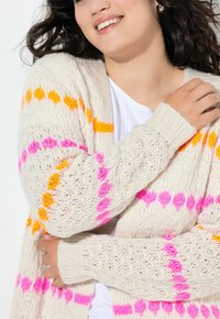 Lys beige strikket cardigan med lyse orange og pink mønstre. Løs pasform med ribbede manchetter og en tekstureret vævning.