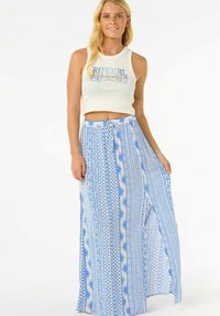Top corto blanco con texto azul y una falda larga y fluida azul y blanca con un patrón de diseños geométricos y motivos de sol.