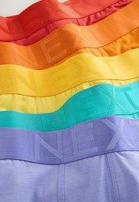 Cinq paires de boxers aux couleurs vives en rouge, orange, jaune, bleu sarcelle et violet, avec des ceintures marquées "NEXT", superposées horizontalement.