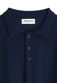 Polo en tricot bleu marine avec un col, comportant une patte de boutonnage avec trois boutons, et une étiquette affichant "FRILIVIN" et la taille M.