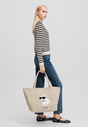Borsa a spalla in tela beige con un gatto dei cartoni animati con occhiali da sole. La borsa ha manici robusti e una forma rettangolare spaziosa.