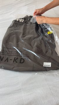 Black eco-friendly bag made from 100% recycled material, partially opened, with visible branding and product information on the packaging.