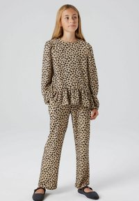 Kostim iz dveh delov s leopardjim vzorcem, ki ima bež osnovo z črnimi madeži, dolgo majico s čipkastim robom in usklajene hlače.