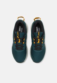 Baskets de sport teal avec des accents noirs et des lacets orange. Tige en mesh, semelle en caoutchouc et détails texturés sur le bout et le talon.