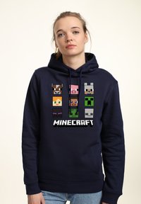 Felpa blu navy con personaggi pixelati di Minecraft in diversi colori sulla parte anteriore. Presenta un cappuccio con stringa e tasca frontale.