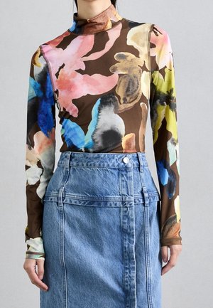 Haut manches longues à col montant avec un motif floral abstrait multicolore, associé à une jupe en denim taille haute avec des boutons et des détails de coutures.