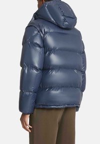 Giacca imbottita blu navy con finitura lucida, cappuccio e design trapuntato. Caratterizzata da una vestibilità comoda e polsini elastici per mantenere il calore.