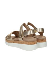 Gouden metallic sandalen met gekruiste bandjes, kurken middenzool, witte rubberen buitenzool en een gladde bovenkant.