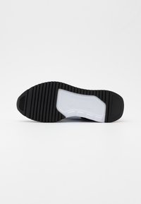 Black and white sneaker sole with textured black rubber and a white cushioned midsole, featuring a ridged pattern for traction.