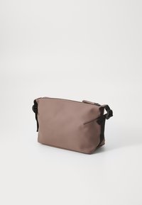 Sac étanche marron de forme rectangulaire, texture lisse, fermeture éclair à l'avant et accents de sangle noire ajustable sur les côtés.