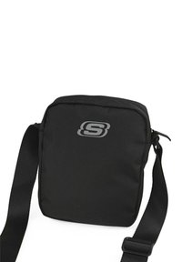 Bolso mensajero negro hecho de tela duradera, de forma rectangular, con cierre de cremallera, correa ajustable y un logo plateado en el frente.