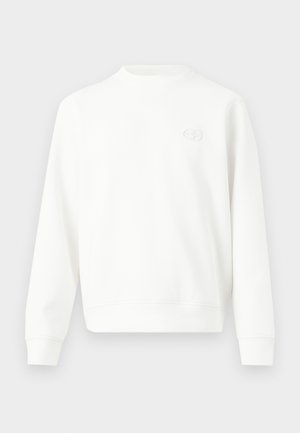 Hvit genser med rund hals og lange ermer, ribbestrikkede mansjetter og nederkant, med en liten brodert logo på venstre bryst.