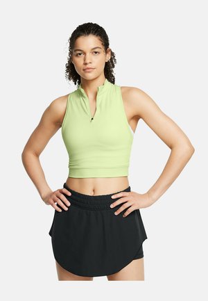 Lys grøn ærmeløs crop top med en frontlynlås, parret med en sort, elastisk talje, lagdelt nederdel. Glat stofstruktur.