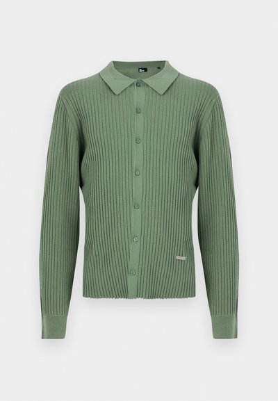 Πλεκτή ζακέτα σε ανοιχτό πράσινο με κλασικό γιακά, μπροστινό κλείσιμο με κουμπιά και ετικέτα της μάρκας στο κάτω αριστερό μέρος. Απαλή υφή.