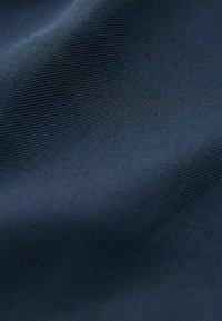 Marineblåt stof med en glat tekstur og fint ribbet mønster, der subtilt reflekterer lys og fremhæver dets vævede struktur.