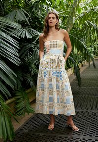 Strapless maxikjole med flerfarvede blomster- og geometriske mønstre, indsnævret talje og lommer. Fremstillet af let, tekstureret stof.