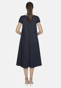 Granatowa sukienka do kolan z krótkimi rękawami i rozkloszowanym krojem w kształcie litery A. Gładka tekstura, minimalne szwy i detale z tyłu.