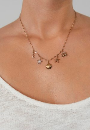 Collier en ton or avec une chaîne ornée de cinq breloques : un hippocampe, une tortue, un coquillage, une étoile de mer et un crabe, chacune avec des détails distincts.