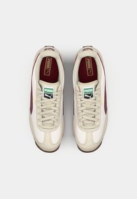 White and maroon sneakers feature a smooth leather upper, round toe, contrasting Puma logos, and light-colored laces. Rubber outsole.