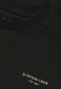 Black crewneck sweatshirt made of soft cotton, featuring ribbed neckline and gold embroidered logo "JJ DENIM CREW" with "Est. 1990."