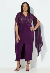 Fialové šaty dlouhé až na zem s korzetem zdobeným flitry, rukávy z lehkého šifonu a předním rozparkem. Kombinovány se stejně fialovými sandály na podpatku.