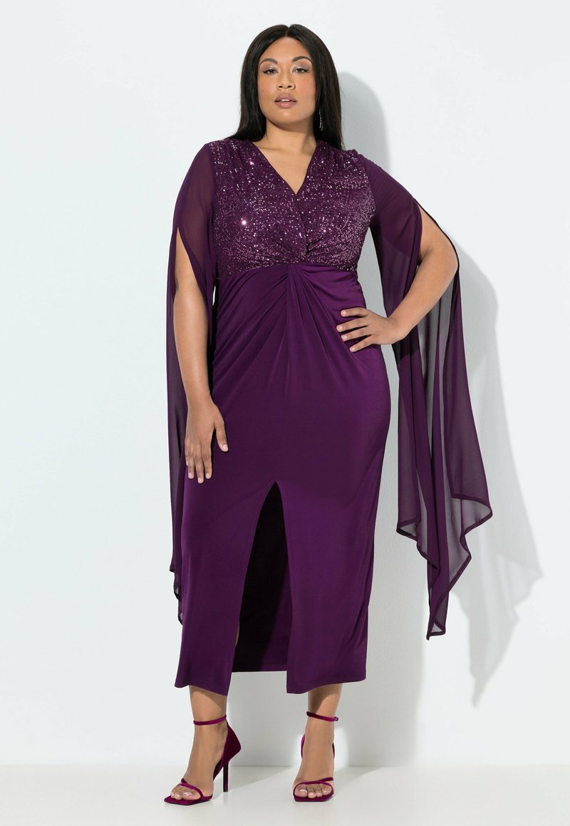 Fialové šaty dlouhé až na zem s korzetem zdobeným flitry, rukávy z lehkého šifonu a předním rozparkem. Kombinovány se stejně fialovými sandály na podpatku.