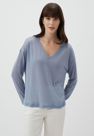Haut long à manches longues bleu clair en V, fabriqué en tissu fin et doux. Il présente une coupe décontractée avec des épaules tombantes et une texture lisse.