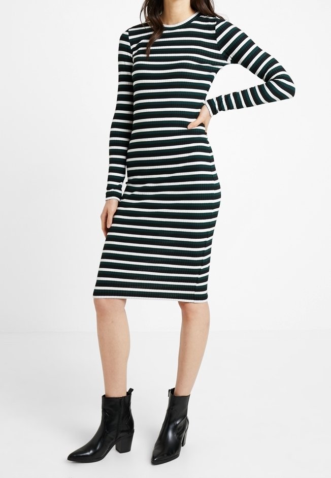 Abito a maniche lunghe a righe in verde e bianco, realizzato in tessuto a coste, forma aderente, lunghezza fino al ginocchio, abbinato a stivaletti neri con tacco.