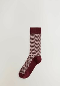 Burgundi színű zoknik, kontrasztos fehér zigzag mintával. Puha anyagból készültek, bordás felsőrésszel a kényelmes illeszkedésért.