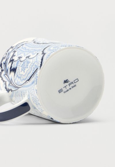 Tasse en porcelaine aux motifs floraux complexes bleu et blanc, posée sur le côté, montrant l'inscription "ETRO Made in Italy" sur le fond.