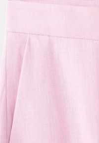 Tela de lino rosa claro con una costura visible y un pliegue suave, mostrando detalles de textura y costura.