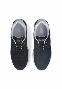 Zapatillas deportivas negras con materiales de malla y gamuza, diseño redondeado, acentos blancos y cordones negros. Logo de la marca visible en la lengüeta.