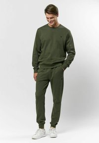 Olivza zaļš džemperis un bikses, kas izgatavotas no mīkstiem audumiem ar ribotām malām. Komplektā ir neliels logos uz krūšu un saskaņojamas bikses.