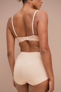 Pfirsichfarbener BH mit Spitzenbesatz und hochgeschnittenen Slips. Glatte Textur, verstellbare Träger und nahtloses Design. Rückansicht mit Fokus auf die Details.