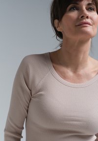 Heledad roosa soonik, millel on pikk varrukas ja ümmargune kaelus, ning raglan varrukad. Pehme tekstuur; keha kuju esitlev, figuuri rõhutav disain.