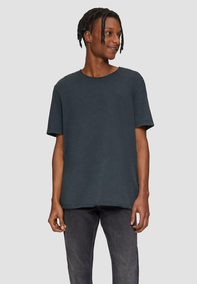 Donkergrijs, oversized katoenen T-shirt met een ronde halslijn en korte mouwen. Heeft zichtbare stiksels en een losse pasvorm.
