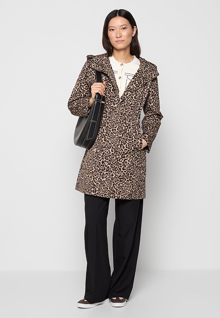Veste en imprimé léopard avec une capuche, des manches longues et des poches avant, associée à un pantalon noir et un sac à épaule assorti.