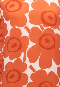 Ενδύμα με κοντά μανίκια, λευκό φόντο με μεγάλα, επαναλαμβανόμενα πορτοκαλί λουλουδένια σχέδια, που διαθέτουν έντονους στρογγυλούς πυρήνες και απαλά άκρα.