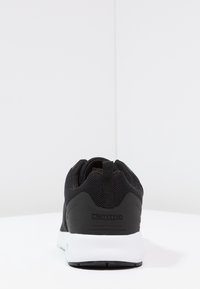 Svart sportig sneakers med textur på ovansidan, vit mellansula och en ögla bak för att dra på skon. Har Kappa-logotyp på hälen.